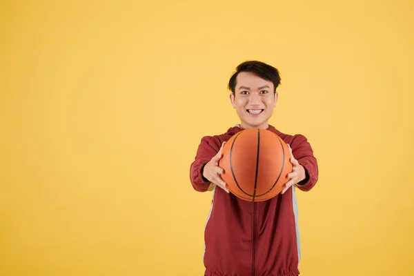 一个兴奋的年轻人拿着篮球拍着镜头笑的画像 — 图库照片