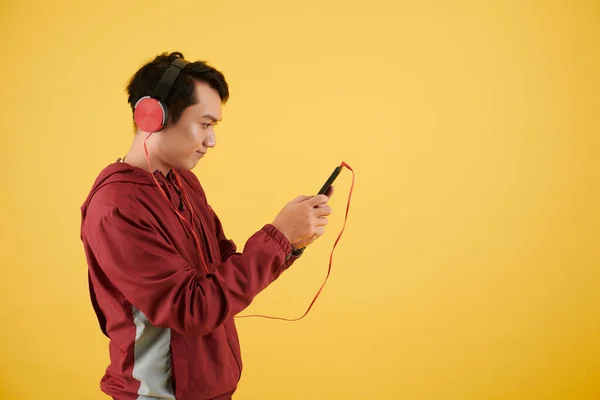 Νεαρός Άνδρας Ακουστικά Ελέγχει Smartphone Και Επιλέγει Μουσική Ακούσει — Φωτογραφία Αρχείου