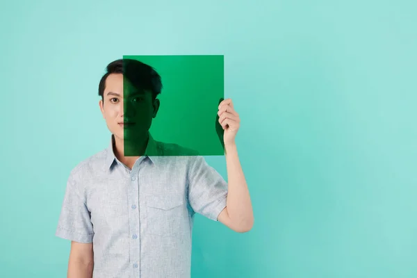 Yüzünün Yarısını Şeffaf Yeşil Plastik Resim Filtresiyle Kaplayan Genç Adam — Stok fotoğraf