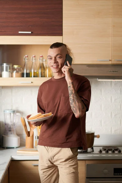 Mutfakta Pişirdiği Sandviçlerle Tabak Taşırken Telefonla Konuşan Genç Bir Adamın — Stok fotoğraf