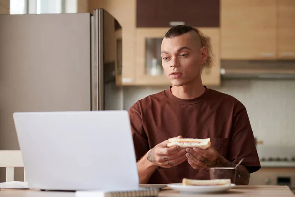 Jeune Homme Mangeant Jambon Fromage Sandwich Regardant Lection Sur Ordinateur — Photo