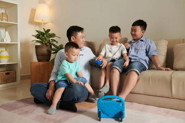 快乐的父亲和他的三个儿子一起在客厅里玩耍 — 图库照片