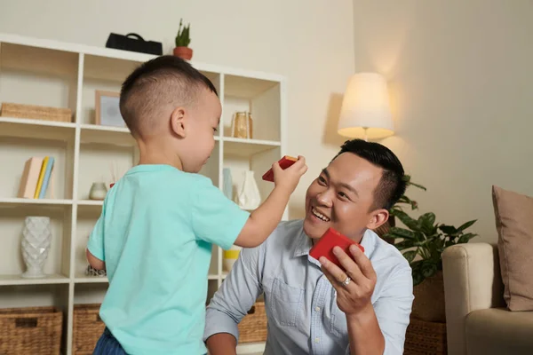 幸せな笑顔ベトナム人男性楽しみますおもちゃのレンガとともに息子と彼の色を教える — ストック写真