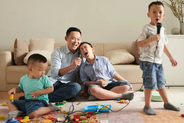 Радостный Талантливый Азиатский Отец Сыновья Поют Микрофоны Дома — стоковое фото