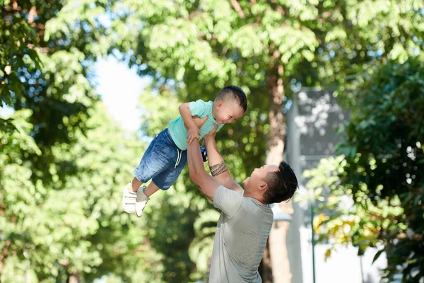 Feliz Padre Levantando Pequeño Hijo Sonriente Cuando Están Caminando Parque — Foto de Stock