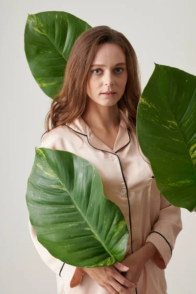 Νεαρή Γυναίκα Μεταξωτές Πιτζάμες Στέκεται Ανάμεσα Μεγάλα Πράσινα Φύλλα — Φωτογραφία Αρχείου