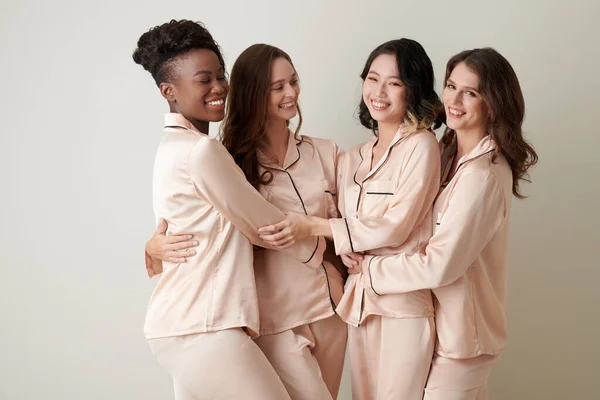 絹のパジャマで女性の友人の多様なグループが笑って抱き合って — ストック写真