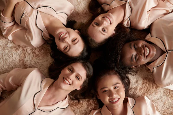 Многонациональная Группа Улыбающихся Молодых Женщин Шелковых Пижамах Лежащих Полу — стоковое фото