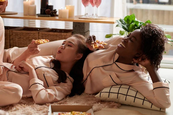 잠옷을 바닥에 의지하고 맛있는 피자를 여성들 — 스톡 사진