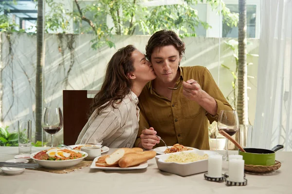 若いです女性接吻ボーイフレンドの頬とき彼あります食べるスパゲッティのために夕食 — ストック写真