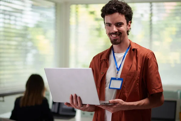 オフィスに立って手にノートパソコンと肯定的なソフトウェア開発者の肖像 — ストック写真