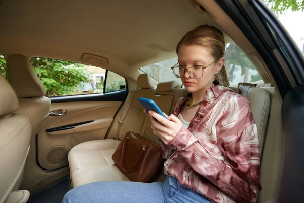 Vážná Mladá Žena Sedí Zadním Sedadle Taxíku Píše Přátelům — Stock fotografie