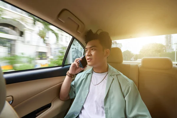 若いベトナム人男性電話で話すとき仕事にタクシーの車に乗る — ストック写真