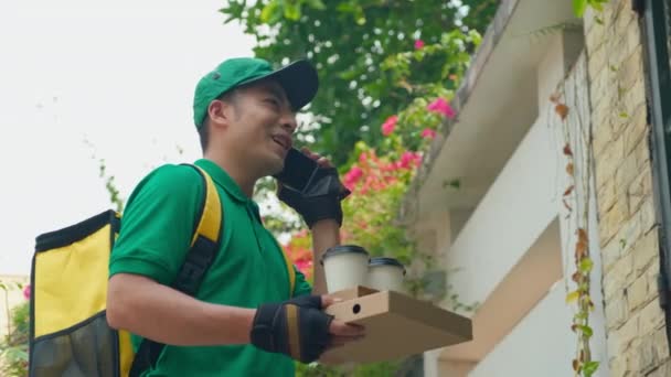 Evin Dışında Yeşil Üniformalı Neşeli Asyalı Teslimatçının Akıllı Telefondan Müşteriyi — Stok video