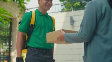 Kadın müşteri, evin dışında yeşil tişörtlü kuryeden paket alıyor.