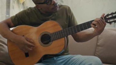 Öğretmeninin evdeki özel derste öğrencisine gitar çalmasını gösteren orta boy bir fotoğraf.