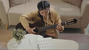 Evde yeni gitar çalmayı öğrenirken öğrencilerin nota almasına tepeden aşağı bakış