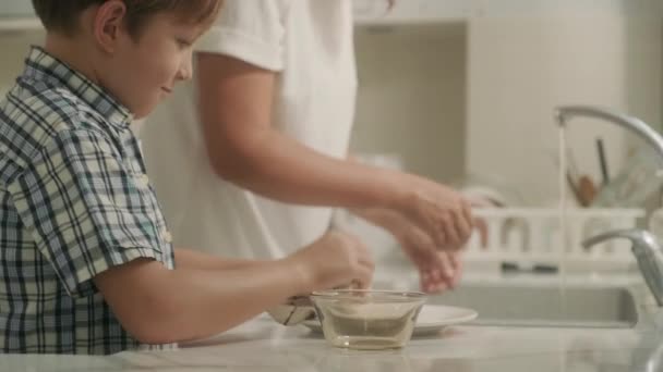 Madre Joven Enseñando Hijo Limpiar Los Platos Después Del Desayuno — Vídeos de Stock