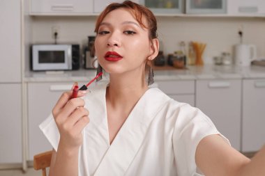 Kırmızı sıvı ruj sürdükten sonra selfie çeken transseksüel kadın.