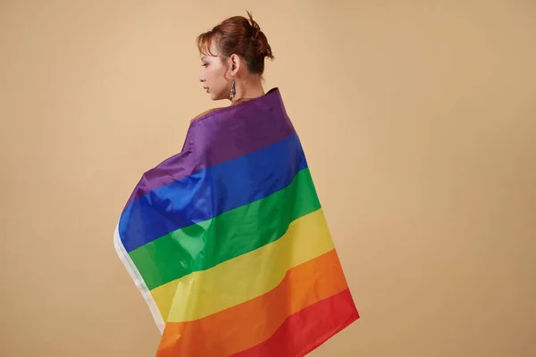 Серйозна Транссексуальна Жінка Загорнута Веселковий Прапор Стоїть Бежевому Фоні — стокове фото