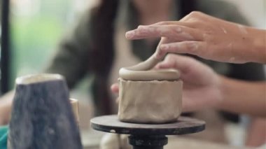 Asya 'lı kadın, atölyede ustanın çömlek çarkında kilden heykel yapmasını izliyor.