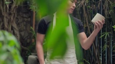 Orta boy Asyalı Adam el yapımı kil çömlek gösterirken ve kameraya bakarken.