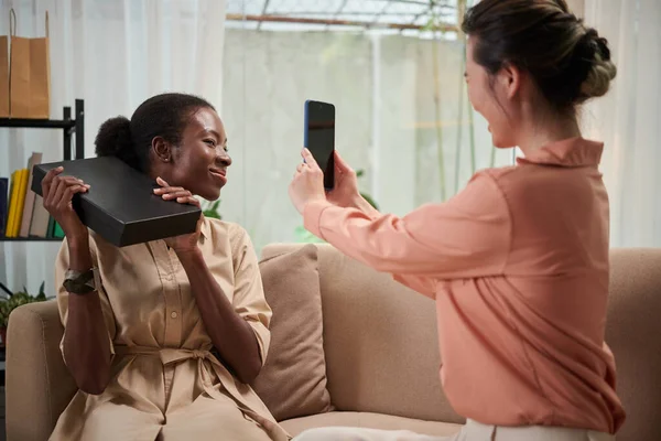 興奮した黒の女性は友人に彼女を撮影するためにボックスからファッションブティック — ストック写真