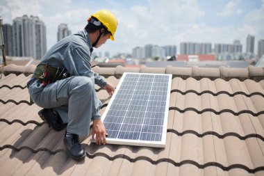Konut binasının çatısına güneş panelleri kuran işçilerin kırpılmış görüntüsü
