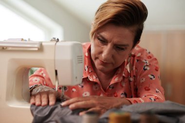 Müşteri için elbise üzerinde çalışırken terzi dikiş makinesi kullanıyor