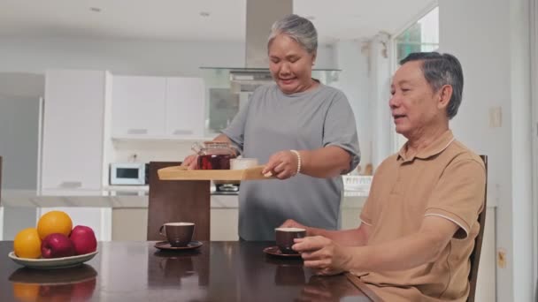 中杯老年妇女在早餐时倒茶给丈夫喝 — 图库视频影像