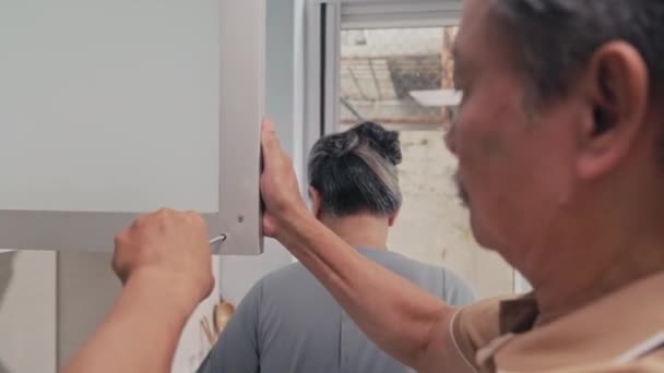 Přes Rameno Pohled Staršího Muže Opravující Dveře Kuchyňské Skříně — Stock video