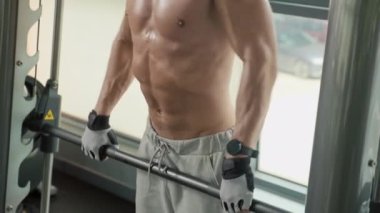 Göbek dekolteli tişörtsüz bir sporcunun spor salonunda kaldırma egzersizi yapması.