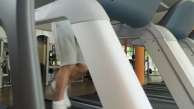 Spor salonunda egzersiz yaparken koşu bandında yüksek hızda koşan atletik adamı yukarı kaldır.