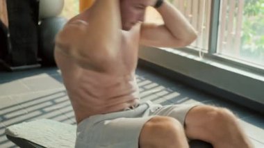 Spor salonunda özel ekipman kullanarak mekik çeken kaslı bir adamın orta boy fotoğrafı.