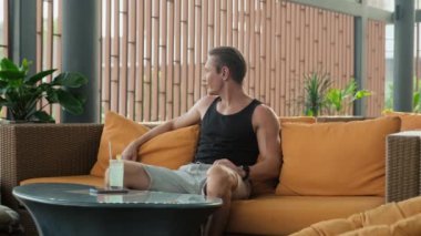 Spordan sonra koltukta oturup kokteyl içen kaslı bir yetişkin.