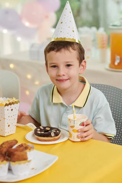 パーティーでドーナツと甘い飲み物を持っている笑顔の誕生日の男の子の肖像 — ストック写真