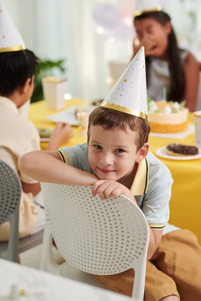 Portret Van Een Lachende Jongen Met Feestmuts Stoel Aan Verjaardagstafel — Stockfoto