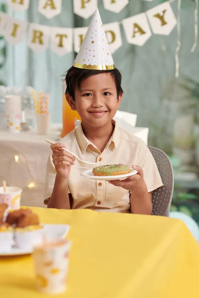 Portret Wesołego Chłopca Jedzącego Oszklone Pączki Przyjęciu Urodzinowym — Zdjęcie stockowe