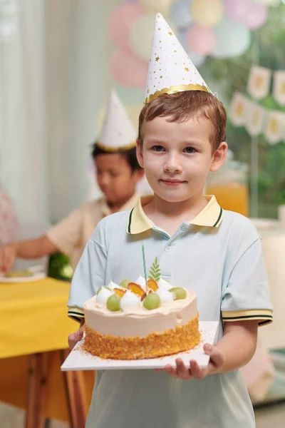 誕生日ケーキを運ぶパーティー帽子の十代の男の子の肖像 — ストック写真