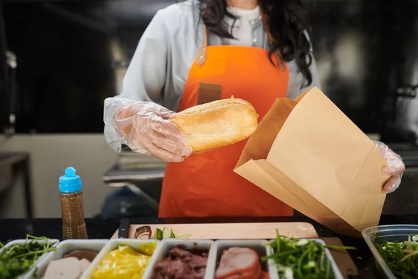 食品トラック労働者は 顧客のための紙袋にサンドイッチを置く — ストック写真