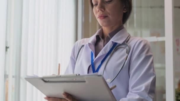 女医生穿着工作服在为在职病人开药方时看着相机的画像 — 图库视频影像