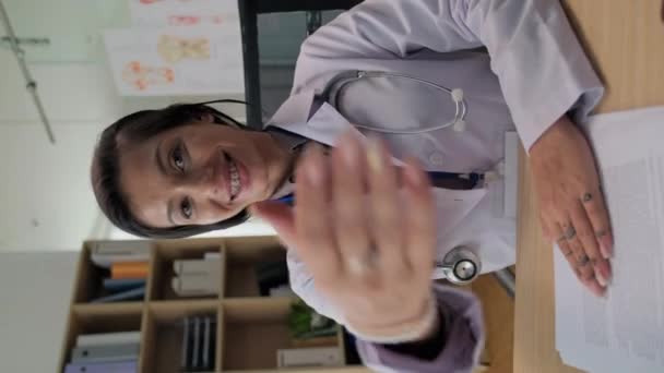 带着矫正器的快乐女医生的垂直画像 要求病人在诊所的橱柜里坐下 — 图库视频影像
