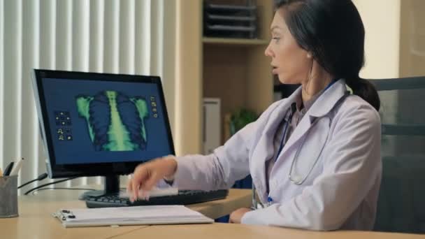 女性放射線科医がX線肺結果を検査し 患者の医療カードにメモを書き込む中撮影 — ストック動画