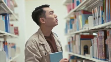 Kütüphane sırasında doğru kitabı arayan birinci sınıf öğrencisinin orta boy fotoğrafı.