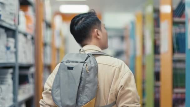 Вид Азиатского Студента Идущего Вдоль Рядов Библиотек Ищущего Правильную Книгу — стоковое видео