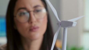 Ofisteki müşteri projesinde çalışırken rüzgar türbininin plastik modeline bakan kadın mühendisi kapat
