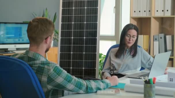 男工程师和女经理坐在办公室里讨论为私人住宅提供太阳能发电项目的细节 — 图库视频影像