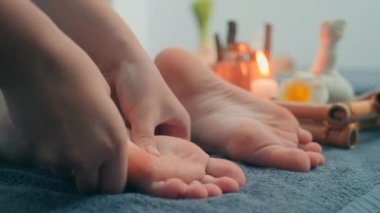 Spa salonundaki terapi seansında müşterinin ayaklarına masaj yapan kadınların yakın görüntüsü.