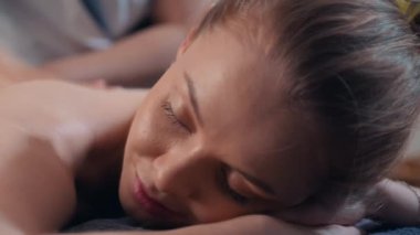 Kadın müşterinin masaj salonundaki yağlarla sırt masajı seansına odaklanması.