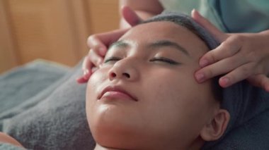 Genç bir kadının güzellik salonundaki spa prosedüründe reşit olmayan bir yüz masajı yaptırdığı yakın çekim.